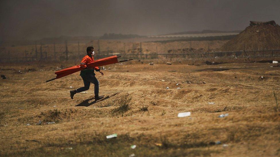 A lone medic runs to a person who was shot along the border fence with Israel as mass demonstrations continue