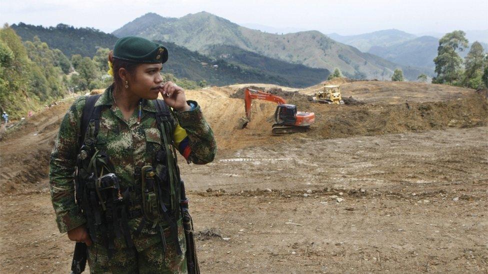 A female Farc rebel stands at a transition zone where diggers are still at work