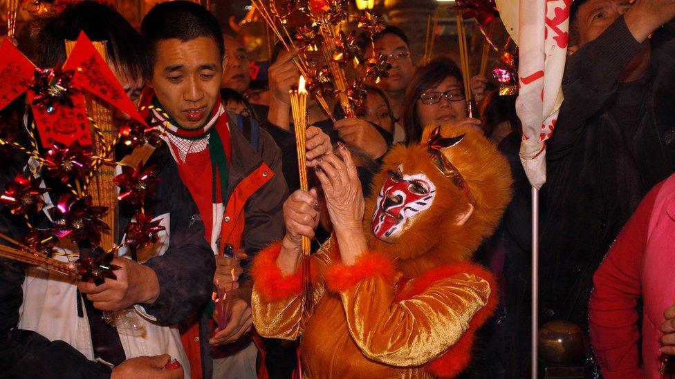 A worshipper dressed as a monkey makes her first offering inside Wong Tai Sin Temple, one of the busiest temples in Hong Kong, China February 7, 2016