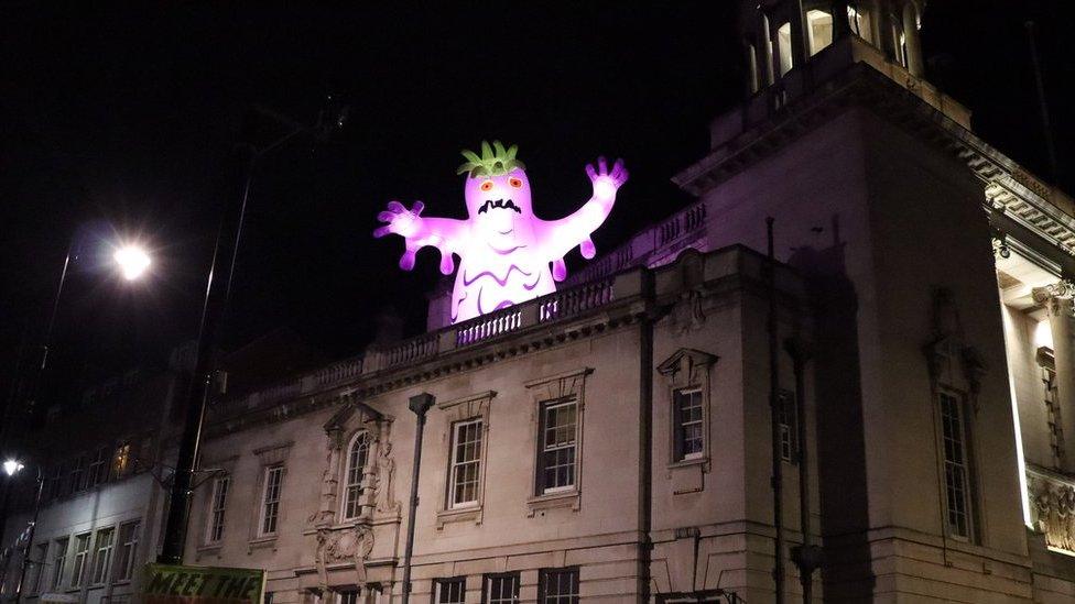 A purple monster at the top of a building