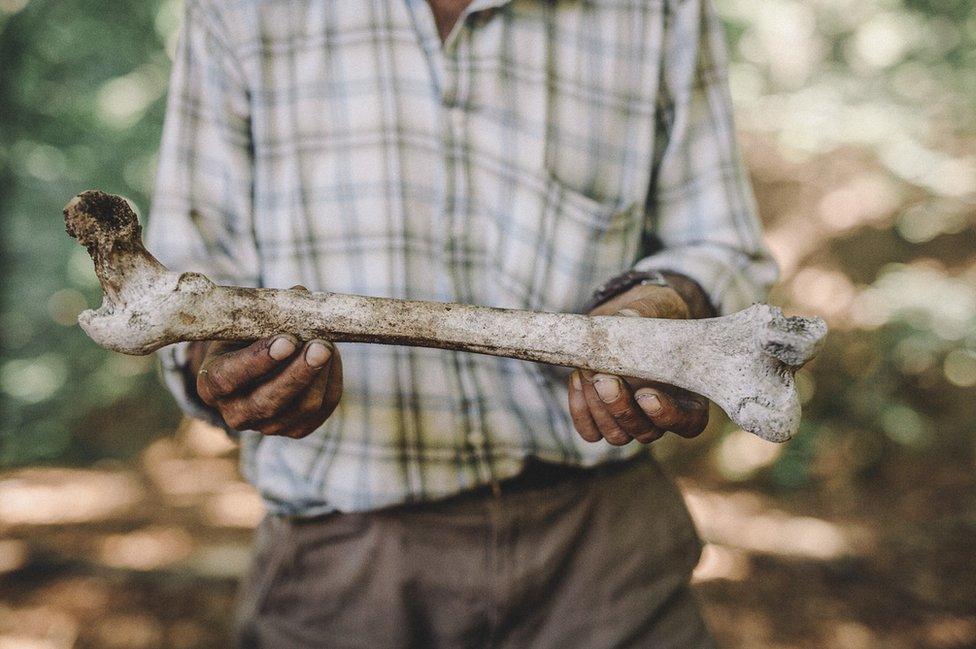 Ramiz holds a human bone.