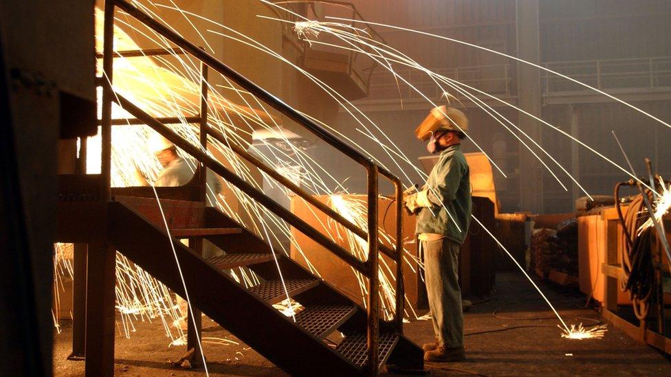 A worker wearing a respirator keeps an eye on molten steel at the TAMCO steel mini mill