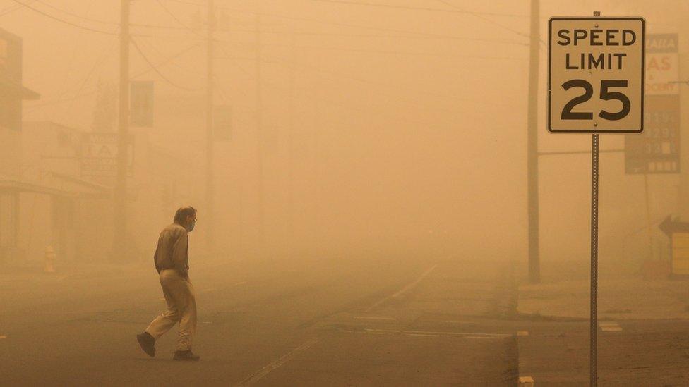 a man walks through air polluted by wildfires