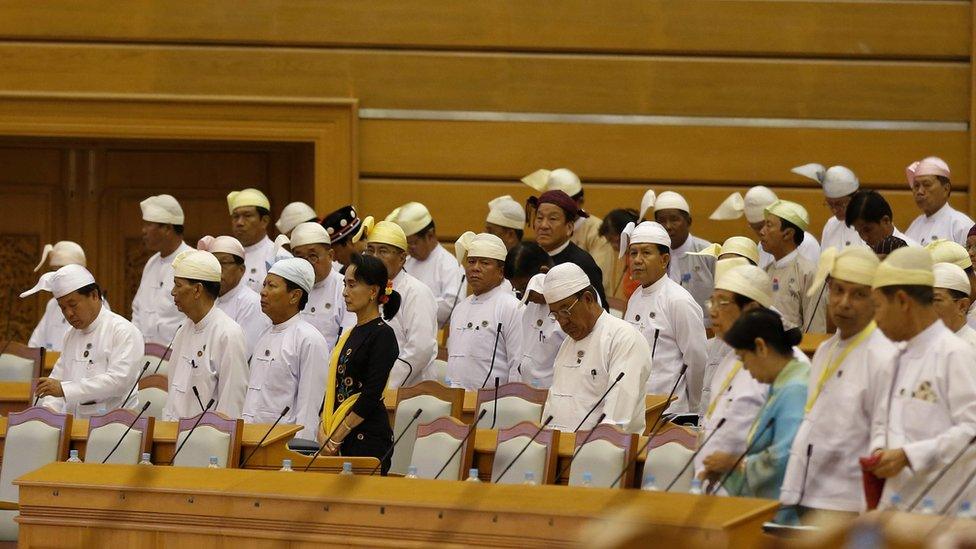 Aung San Suu Kyi surrounded by other politicians at a parliamentary session