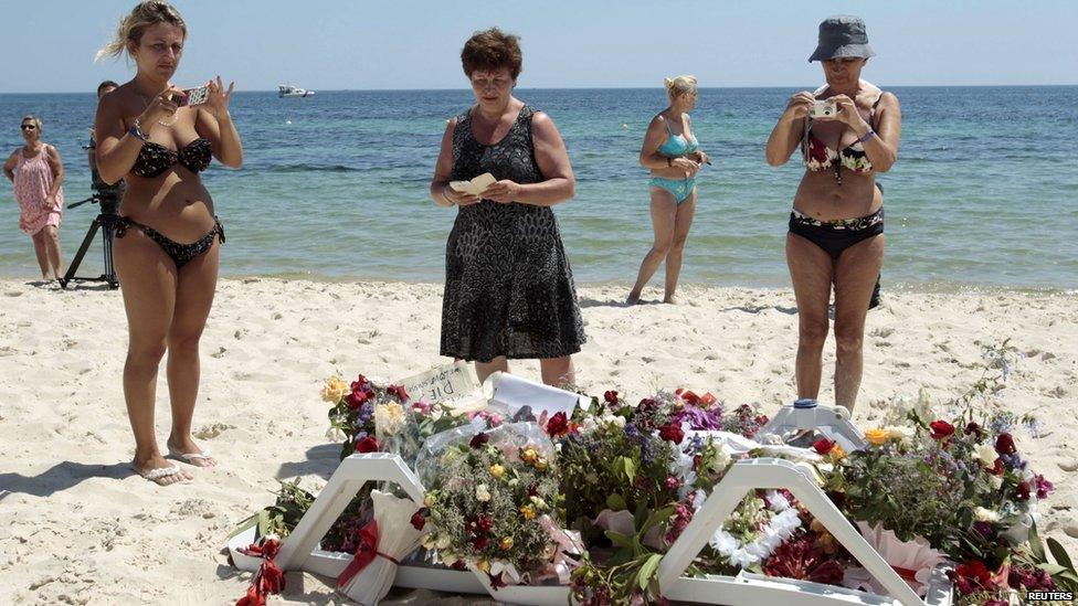 Tourists photograph flowers left at the site of Friday's attack in Tunisia