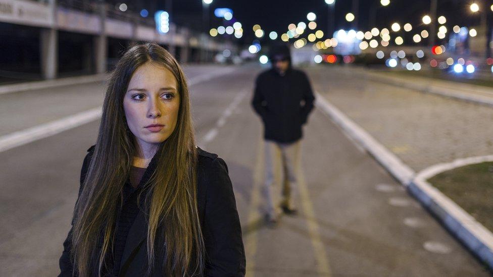 Woman being followed by a man down the street