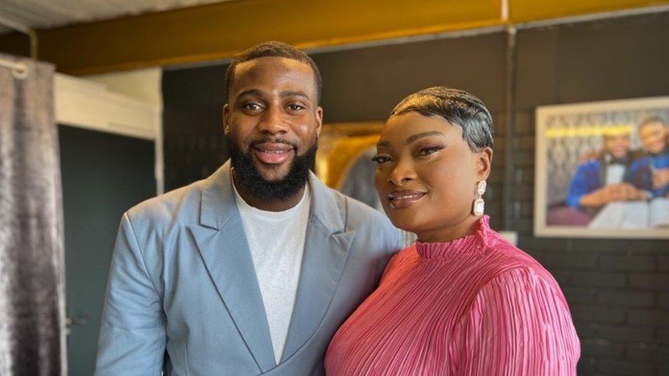 Pastor Onyeka Power wearing a blue suit with his wife wearing a pink dress