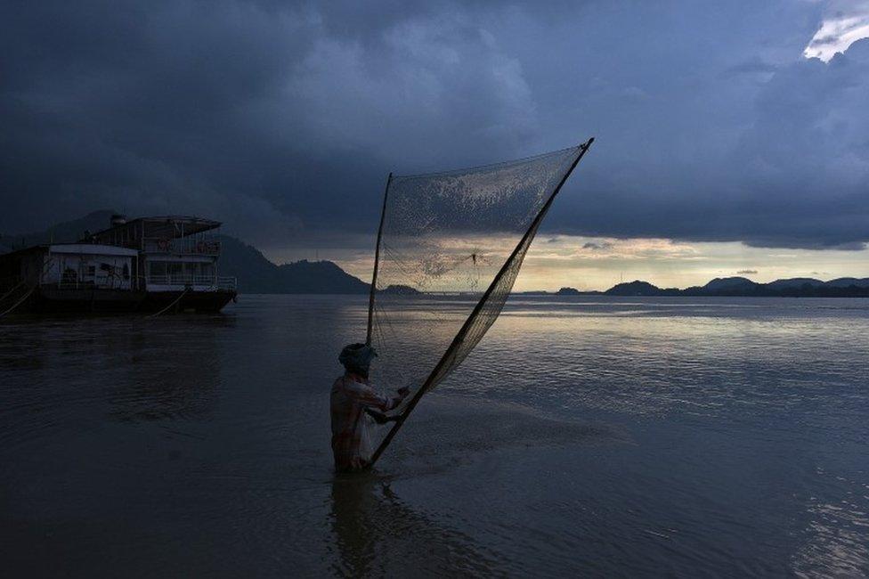 A man catches fish at the banks of the Brahmaputra river in Guwahati, India August 28, 2017