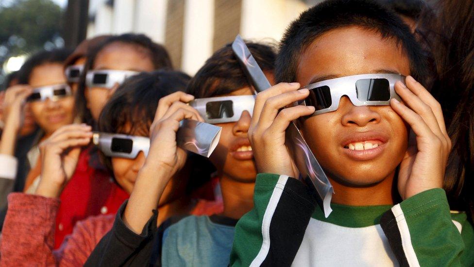 Children watch the eclipse through special protective glasses.