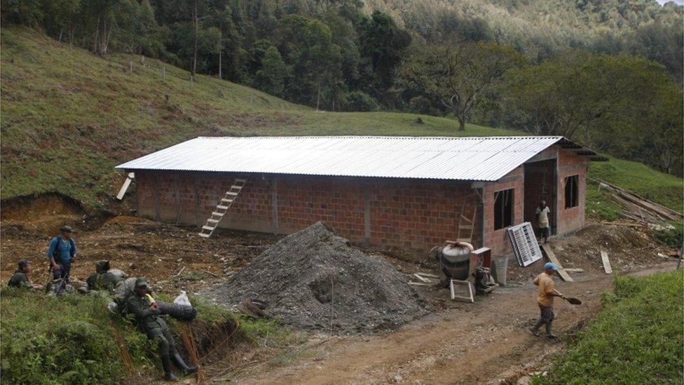 Workers build a house while members of the Farc sit nearby in La Elvira, in Cauca province, Colombia