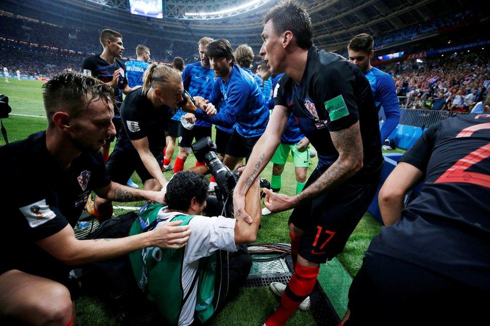 Croatia's Mario Mandzukic helps an AFP photographer Yuri Cortez to his feet after celebrating scoring their second goal