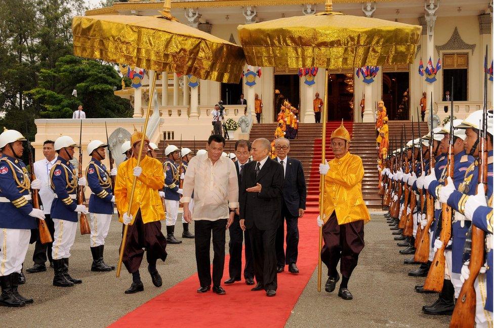 Philippines President Rodrigo Duterte (centre L) and Cambodian King Norodom Sihamoni (centre R) walk past honour guards during a meeting at the Royal Palace in Phnom Penh on December 14, 2016.