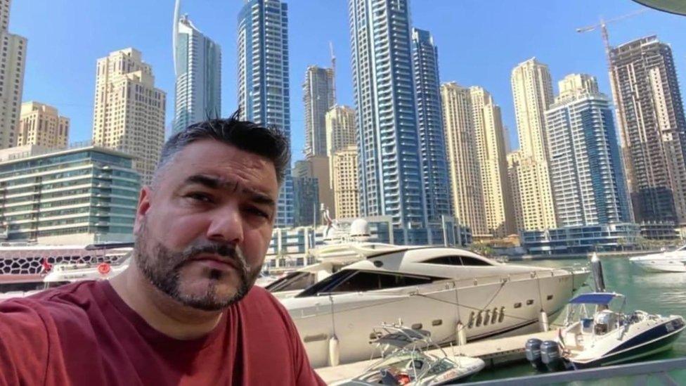 Doede Osman Khan takes a selfie in front of skyscrapers and yachts