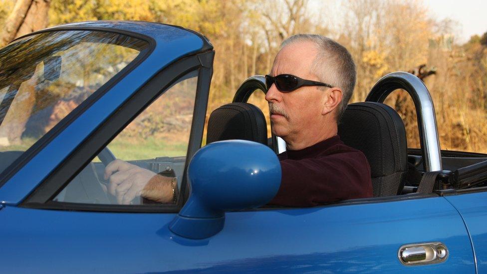 Middle aged man in a sportscar