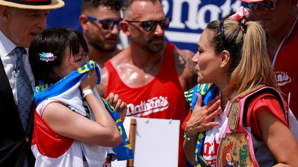 Mayoi Ebihara and World Champion Miki Sudo gesture on the day of 2023 Nathan's Famous Fourth of July International Hot Dog Eating Contest at Coney Island in New York Cit