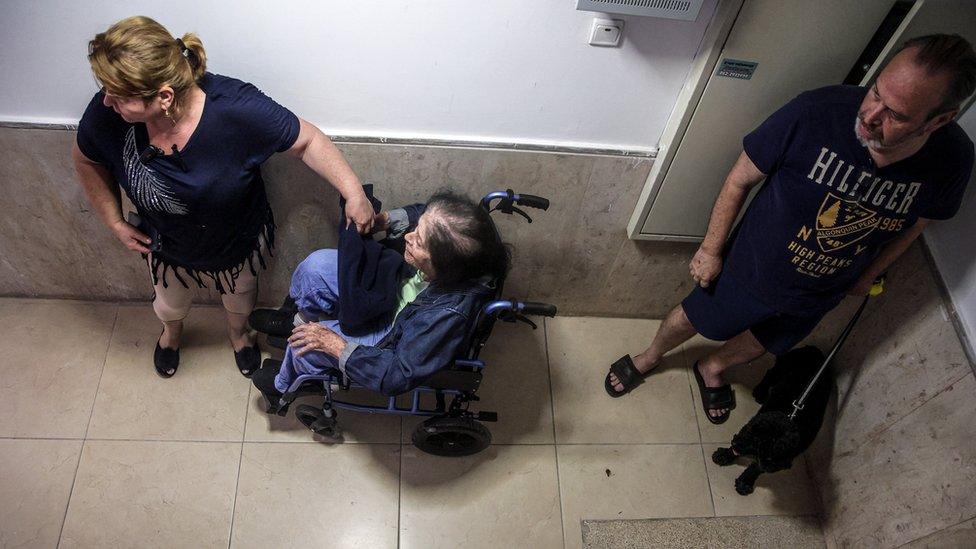 People take shelter in a building block as rockets are launched from the Gaza Strip, in Tel Aviv, Israel