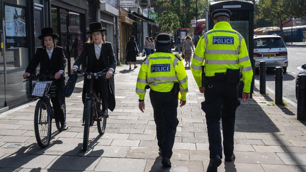 Orthodox Jewish men pass police officers as they patrol around Stamford Hill, an area of London with a large Jewish community, on October 10, 2023 in London, England.