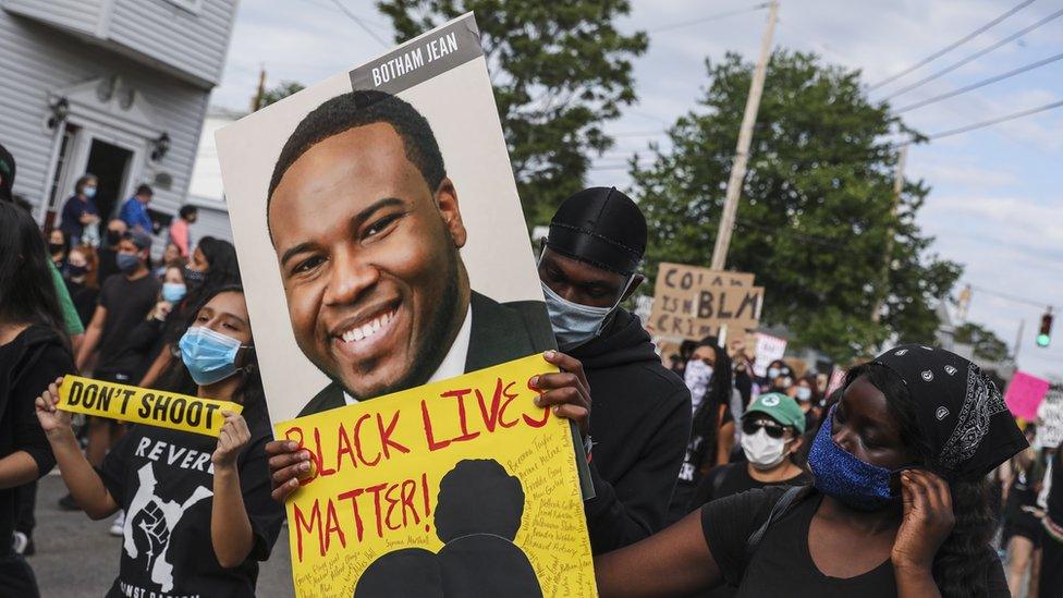 A demonstrator holds a sign for Botham Jean while marching during a demonstration on June 9, 2020