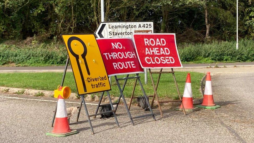 Road signs "road ahead closed" and "no through route" plus directions for diversion