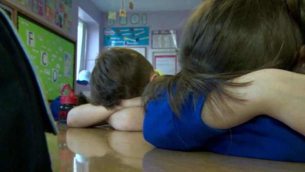 Children with heads on desks