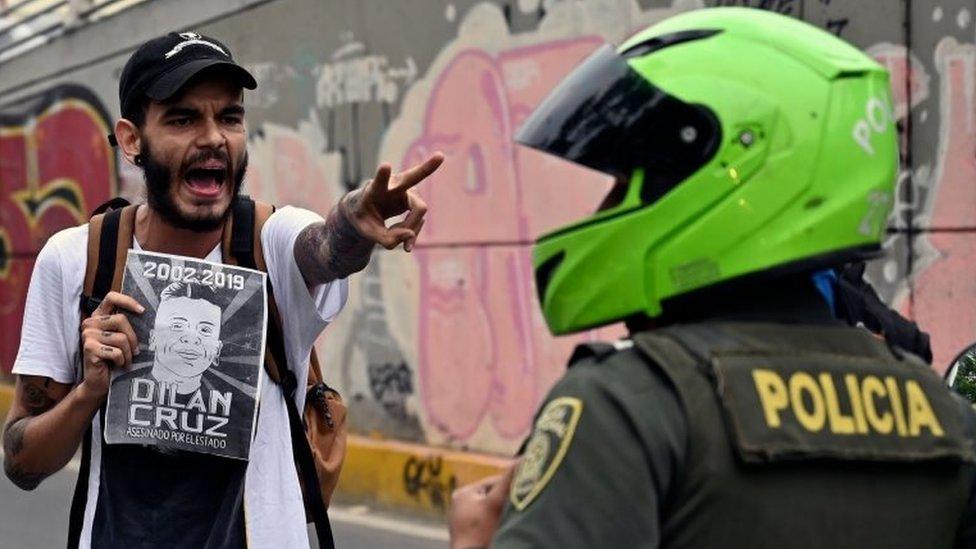 A demonstrator holding a poster of the late Dilan Cruz shouts at riot police during a march against the government of Colombian President Ivan Duque during a national strike in Cali on November 27, 2019