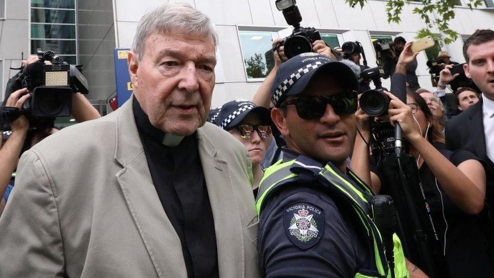 George Pell leaves a court hearing in Melbourne in February, flanked by police and media representatives