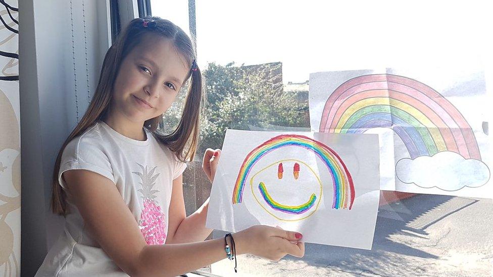 GIRL-WINDOW-HOLDING-RAINBOW-PICTURE.