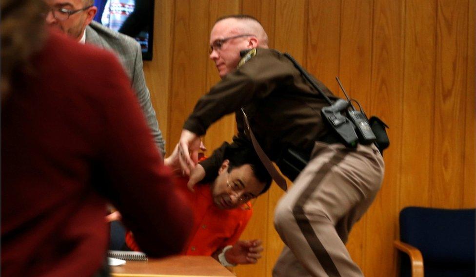 Court security staff try to shield Larry Nassar after the father of three of his victims lunged at him