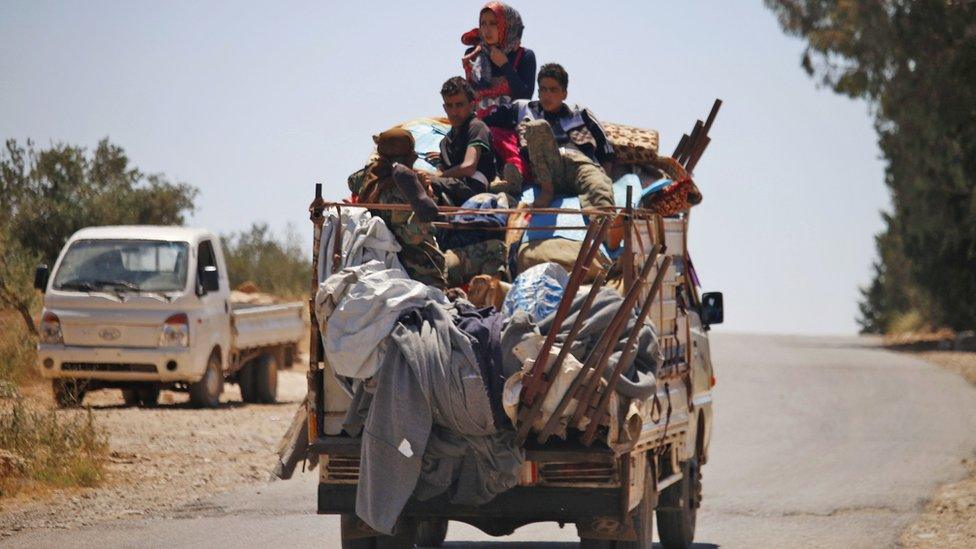 Displaced Syrians sit on a van moving through rebel-held Deraa province (26 June 2018)