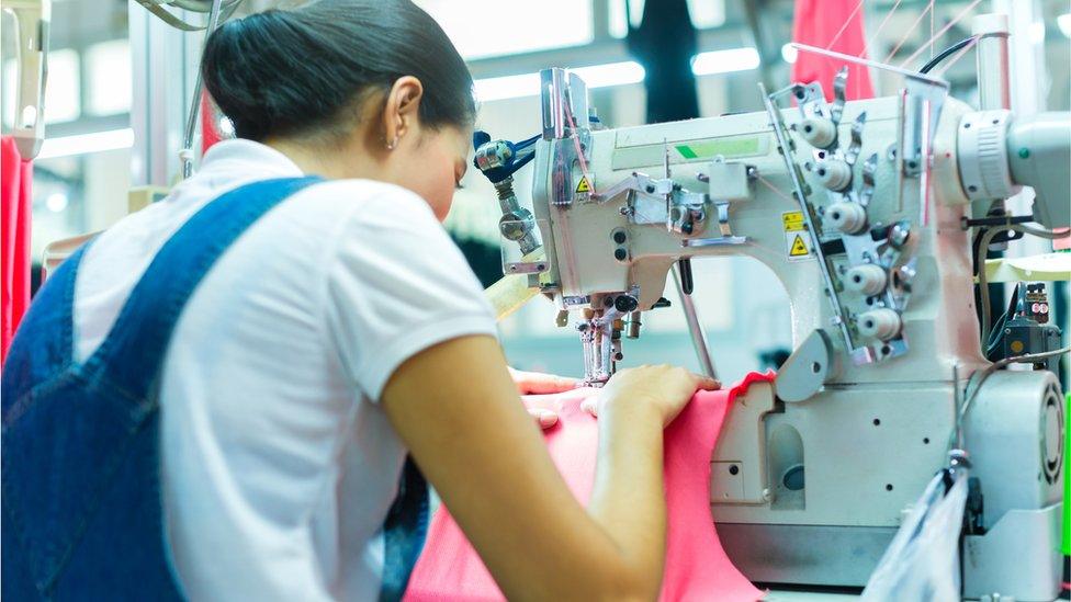 A seamstress sewing a garment in a factory