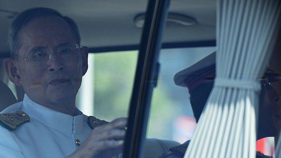 Thai King Bhumibol Adulyadej (L), flanked by his son Crown Prince Maha Vajiralongkorn (R-partly hidden), waves to a crowd of well-wishers as he travels in a motorcade to the Royal Palace