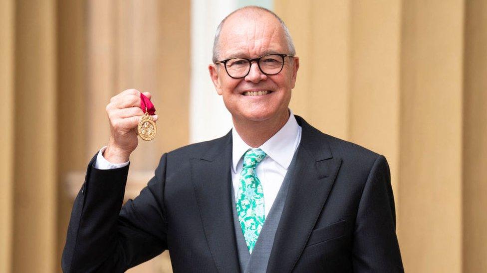 Sir Patrick holding up his award