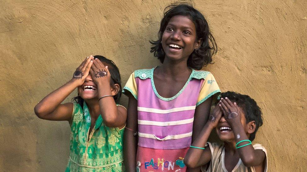 Three-children-two-with-eyes-drawn-on-their-hands.