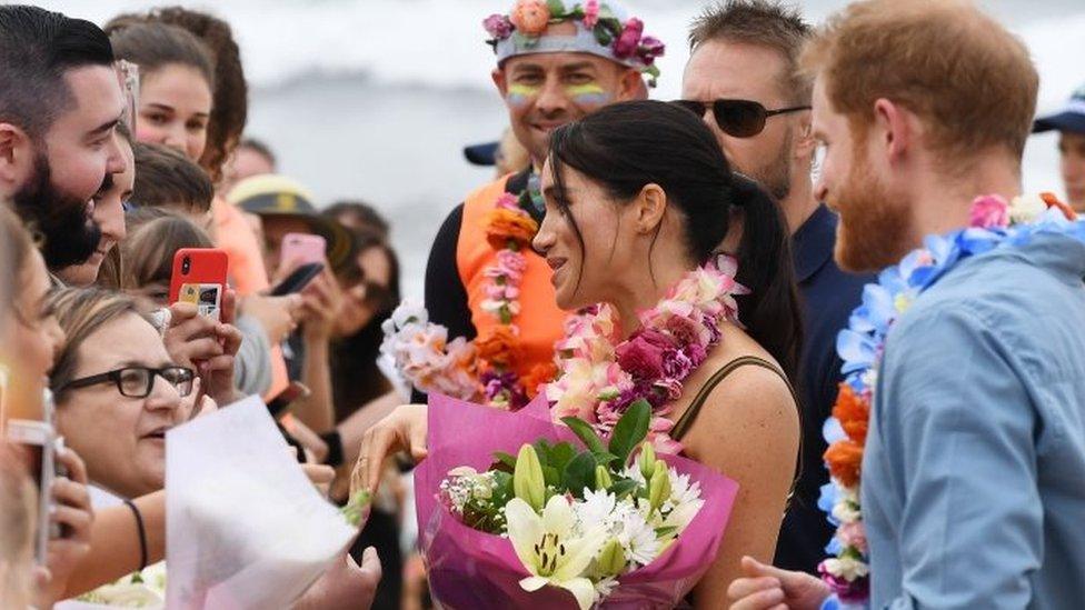 Prince Harry, the Duke of Sussex and his wife Meghan, the Duchess of Sussex receive flowers during a meet the people walk at Bondi Beach, in Sydney, Australia, 19 October 2018.