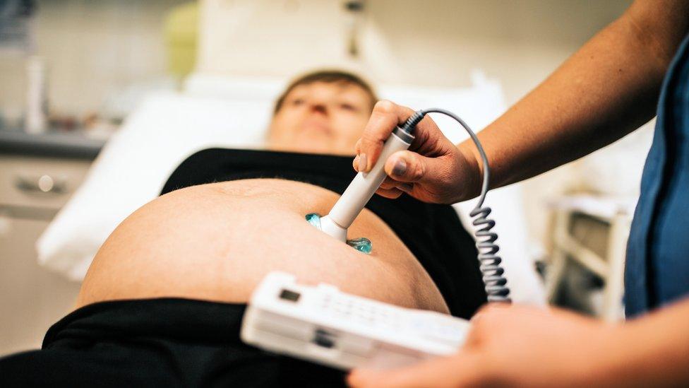 A midwife scans a pregnant woman's stomach