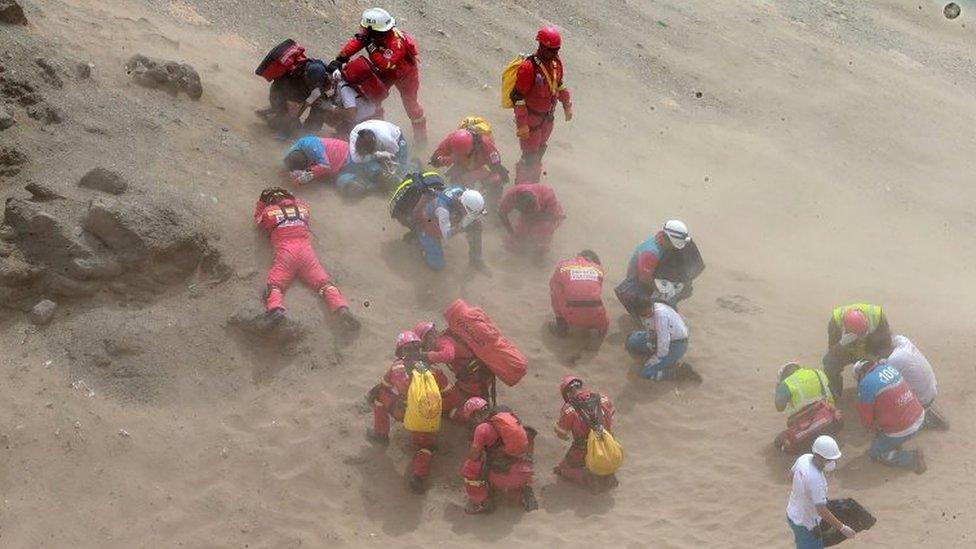 0 A handout photo made available by Agencia Andina shows a group of emergency personnel covering themselves from dust generated by a helicopter during rescue operatons after a passenger bus plunged off the Pan-American Highway North, about 45 kilometers from Lima, Peru, 02 January 2018