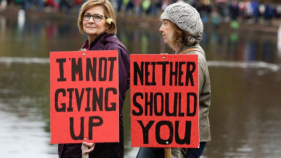 Two women in Seattle hold signs protesting a Trump presidency.