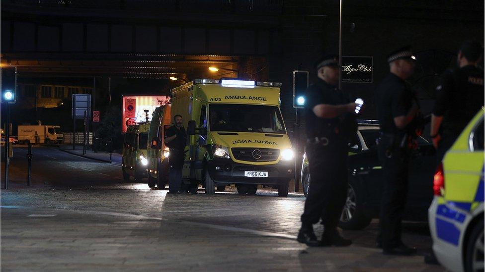 Police officers at the attack scene as ambulances leave