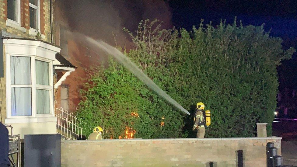 Firefighter sprays a house with water