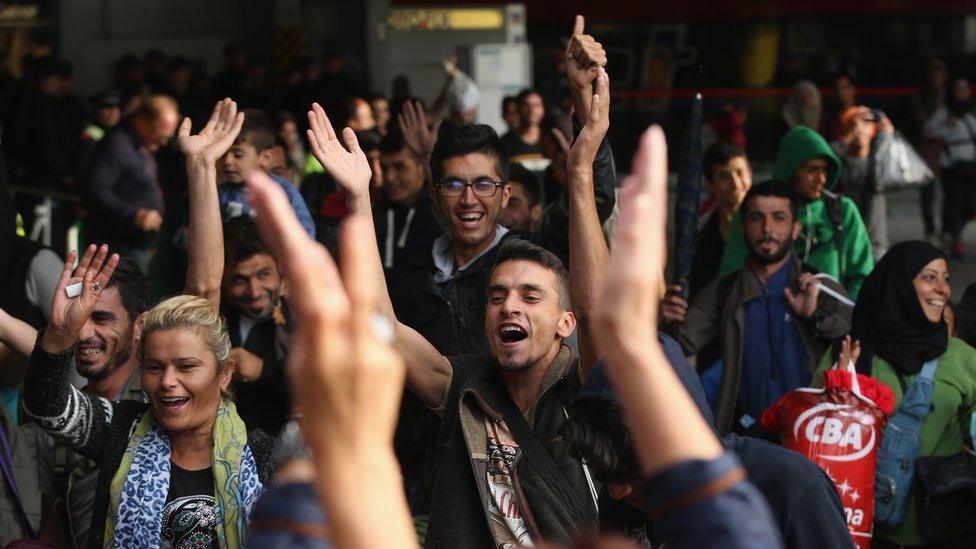 Migrants arriving with approximately 800 others on a train from Hungary react to the welcoming cheers of onlookers at Munich