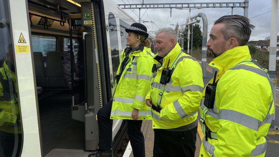 A police officer boards a train with two transport safety officers