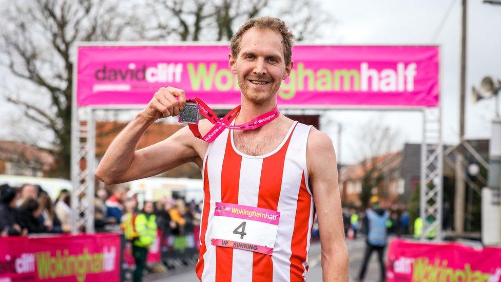 Male runner holding medal