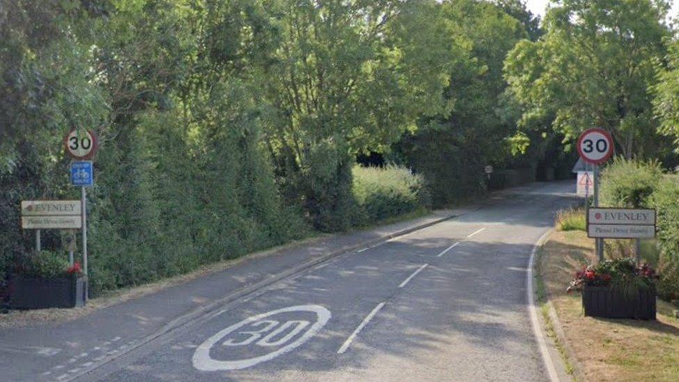 Entrance to Evenley village with 30mph road and hedges either side