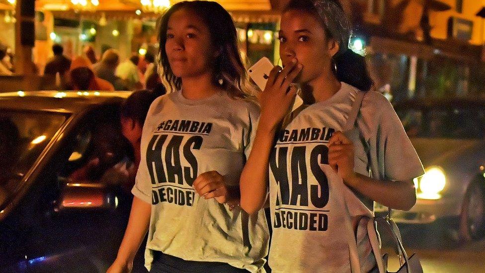 Young women wearing '#GambiaHasDecided' T-shirts walk in streets after hearing of the confirmed departure of former Gambian leader Yahya Jammeh in Banjul on January 21, 2017.