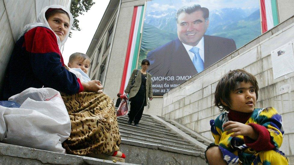 A mother and her children beg on a stairway, beneath a building with a huge poster of Tajik President Emomali Rahmon, 23 October 2006