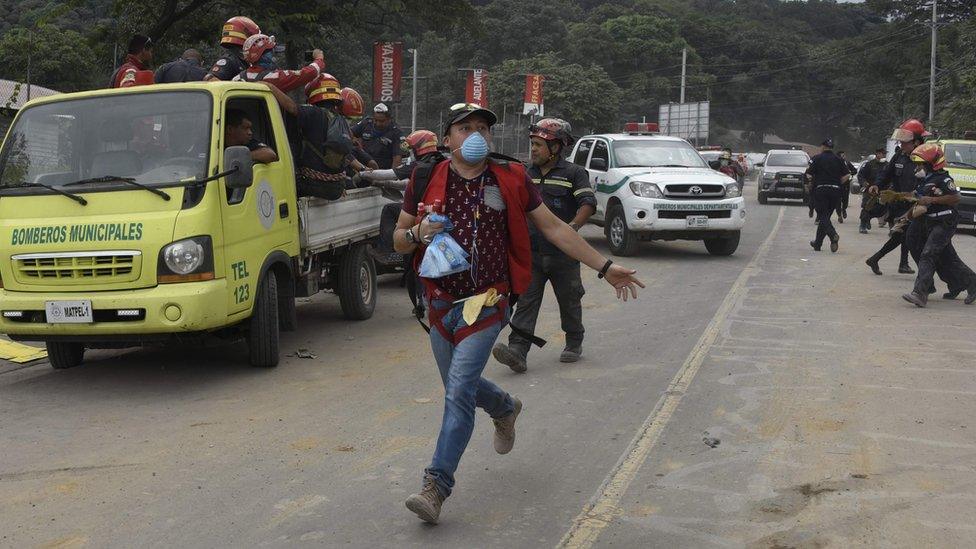 Volunteers and rescuers evacuate the disaster zone as a column of smoke and ash rises from the area where lava flowed down the Fuego Volcano,