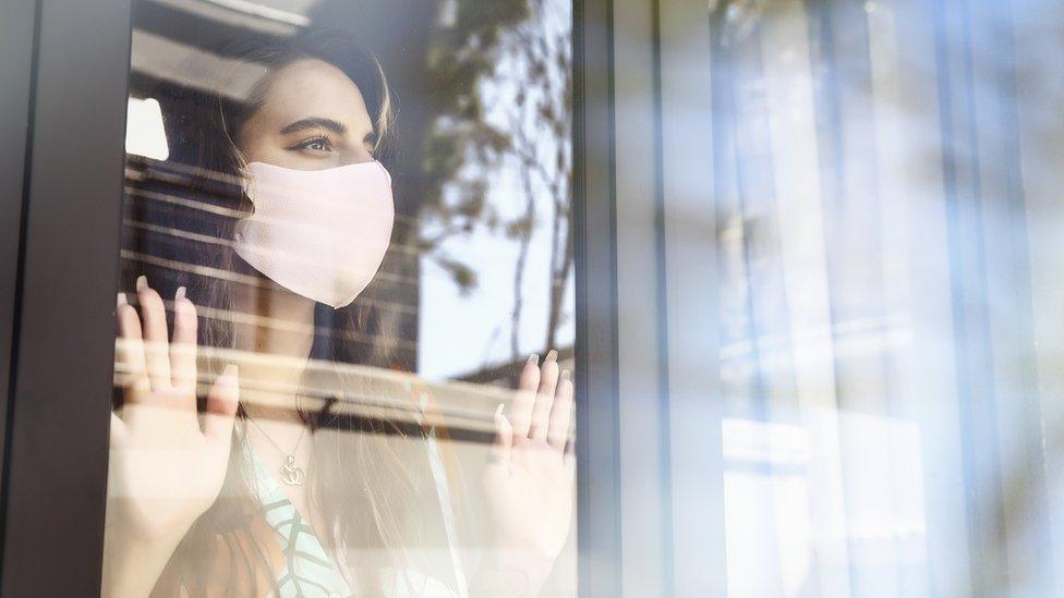 A young woman looks out of her hotel room window while in quarantine for Covid