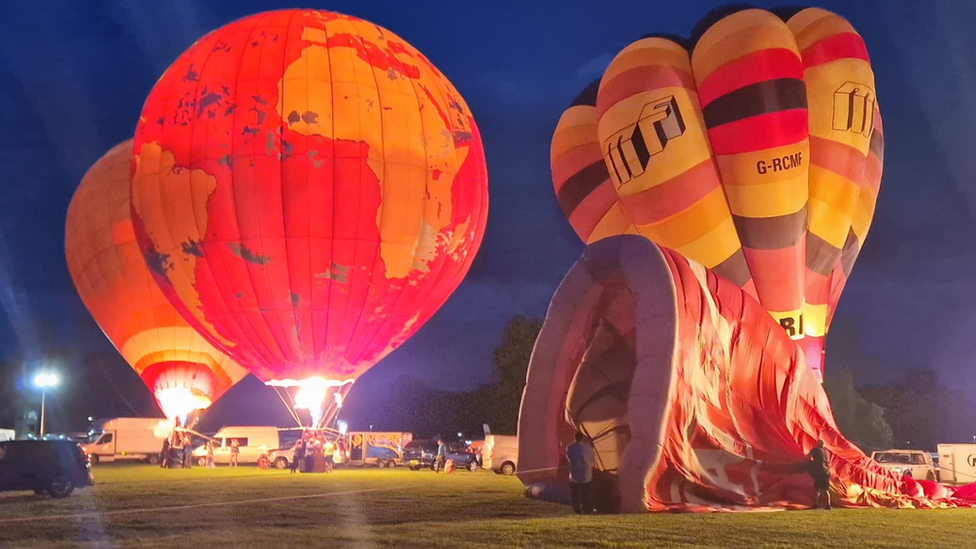 Three hot air balloons in the night in a park