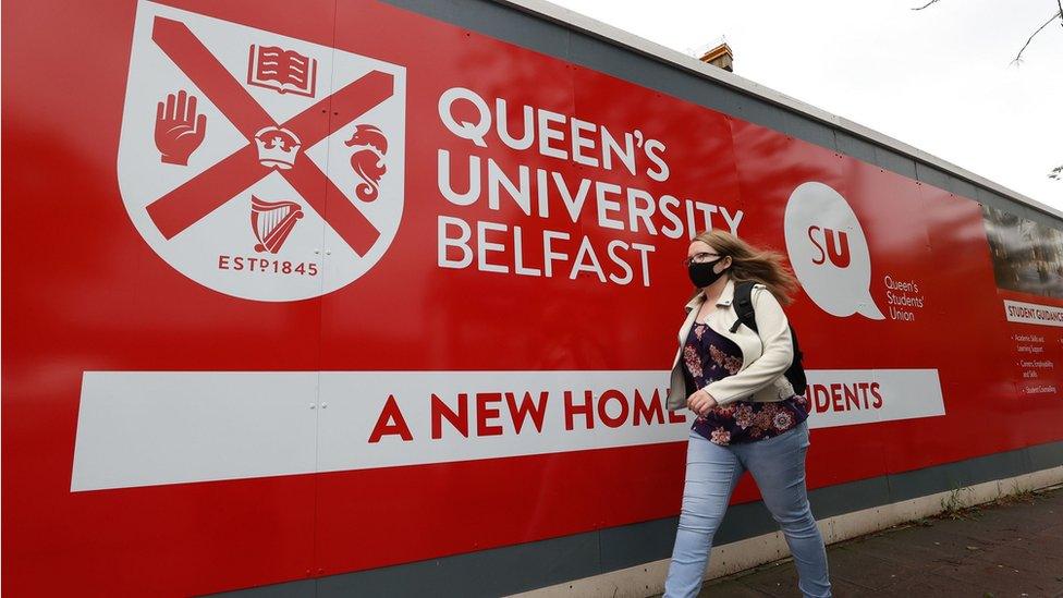 Student walking past QUB sign