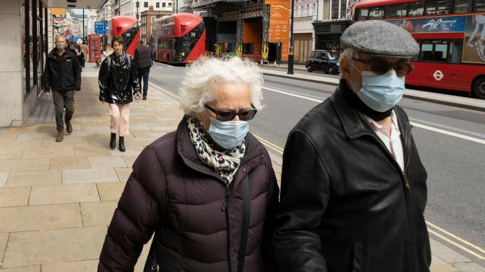 Older people wearing face masks walk along Piccadilly in London